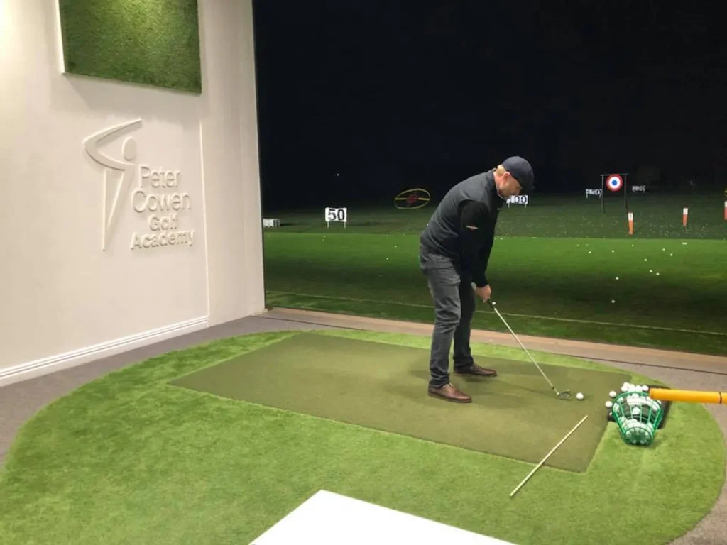 Square driving range mat in an indoor hitting bay