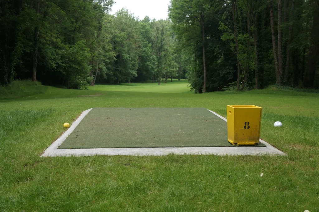 Artificial turf tee box cut to size, with a tee marker