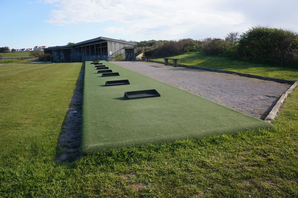 Artificial turf tee line with rubber tees on an outdoor range