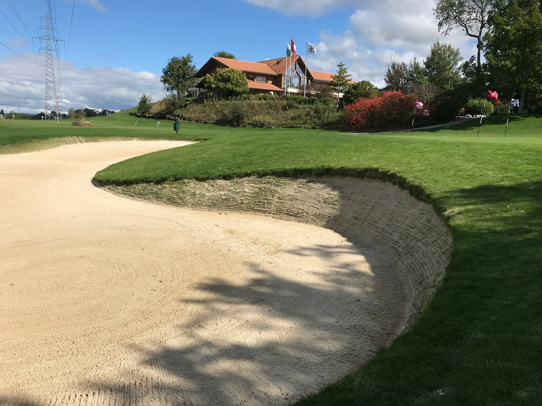 Newly built bunker and green edge in front of a clubhouse